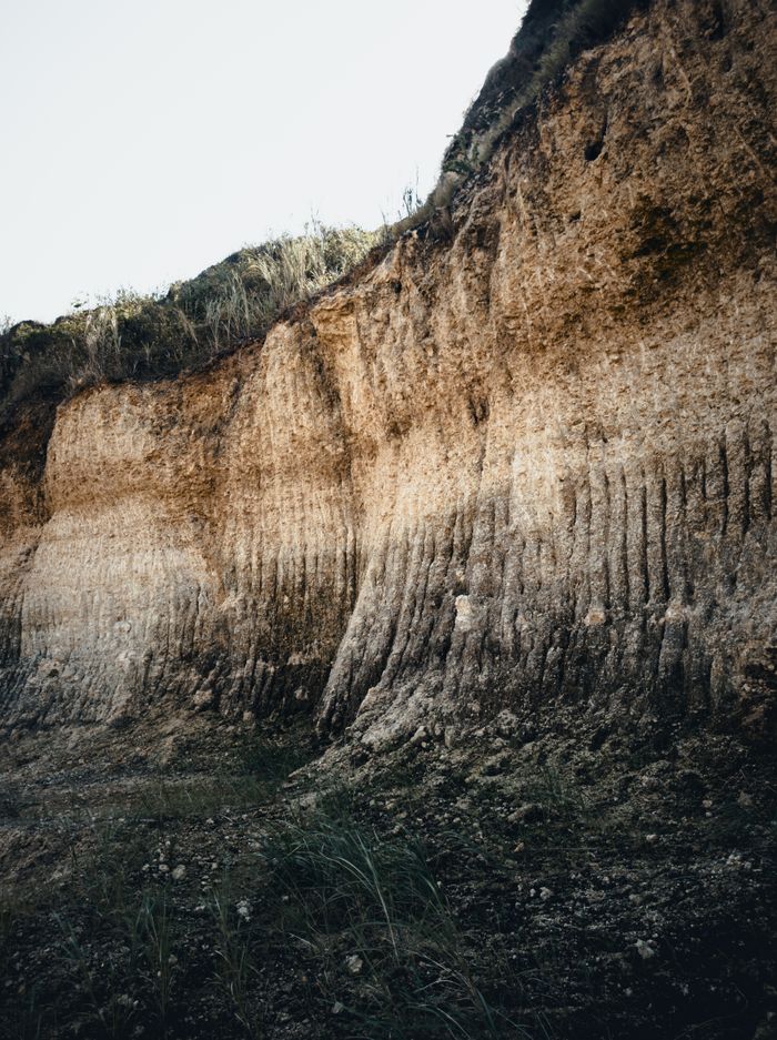 about-us Eroded cliff face showcasing unique layered rock formations captured in natural light.